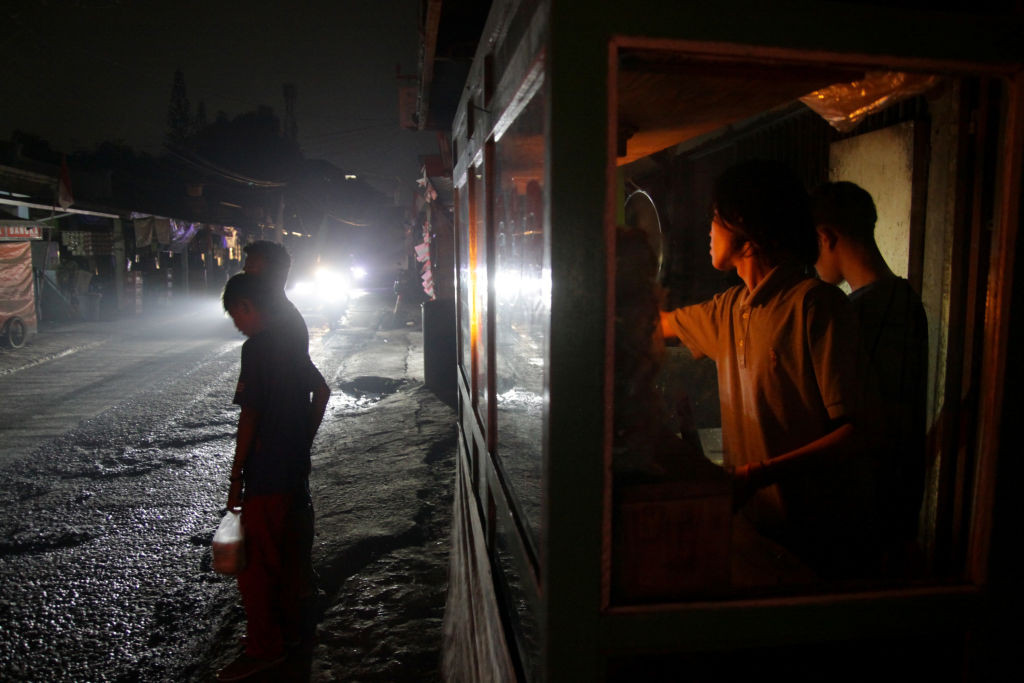 Food vendors serve customers by lantern light on 5 August, the second day of an electricity blackout in Wanasari Village, West Java