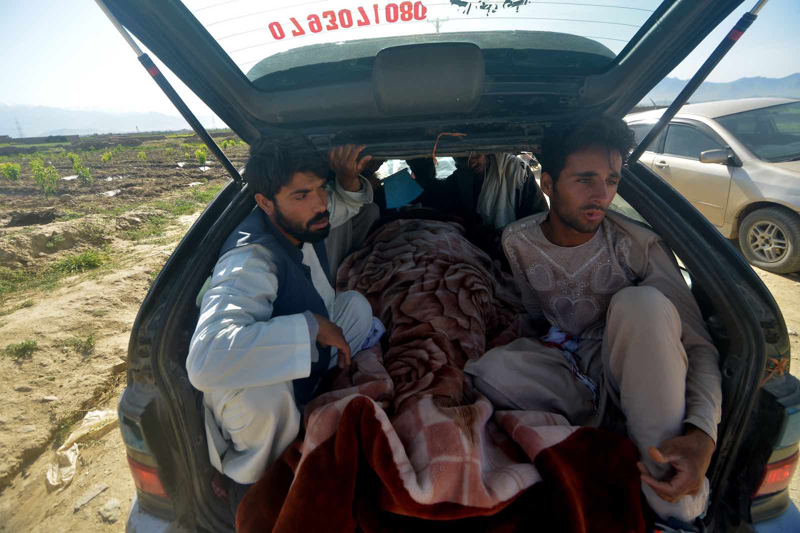 Men sit in car with the body of a victim killed in a 19 May mosque shooting near Kabul, 20 May in Kunduz (Ahmad Sahel Arman/AFP via Getty Images)