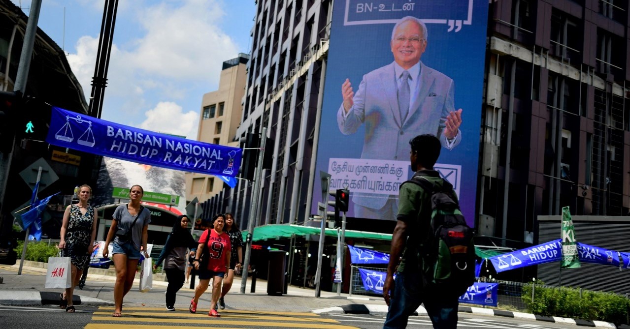 Pedestrians in Kuala Lumpur walk past an election billboard featuring Malaysia’s Prime Minister Najib Razak (Photo: Simon Roughneen)