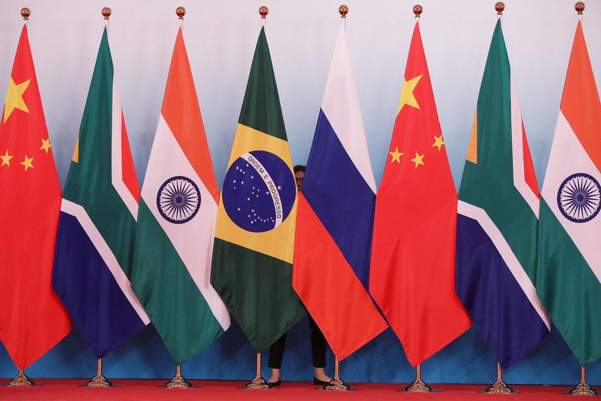 A member of staff stands behind national flags of Brazil, Russia, China, South Africa and India to tidy the flags ahead a group photo during the BRICS Summit at the Xiamen International Conference and Exhibition Center in Xiamen, southeastern China's Fujian Province on September 4, 2017. Xi opened the annual summit of BRICS leaders that already has been upstaged by North Korea's latest nuclear weapons provocation. / AFP PHOTO / POOL / WU HONG (Photo credit should read WU HONG/AFP via Getty Images)