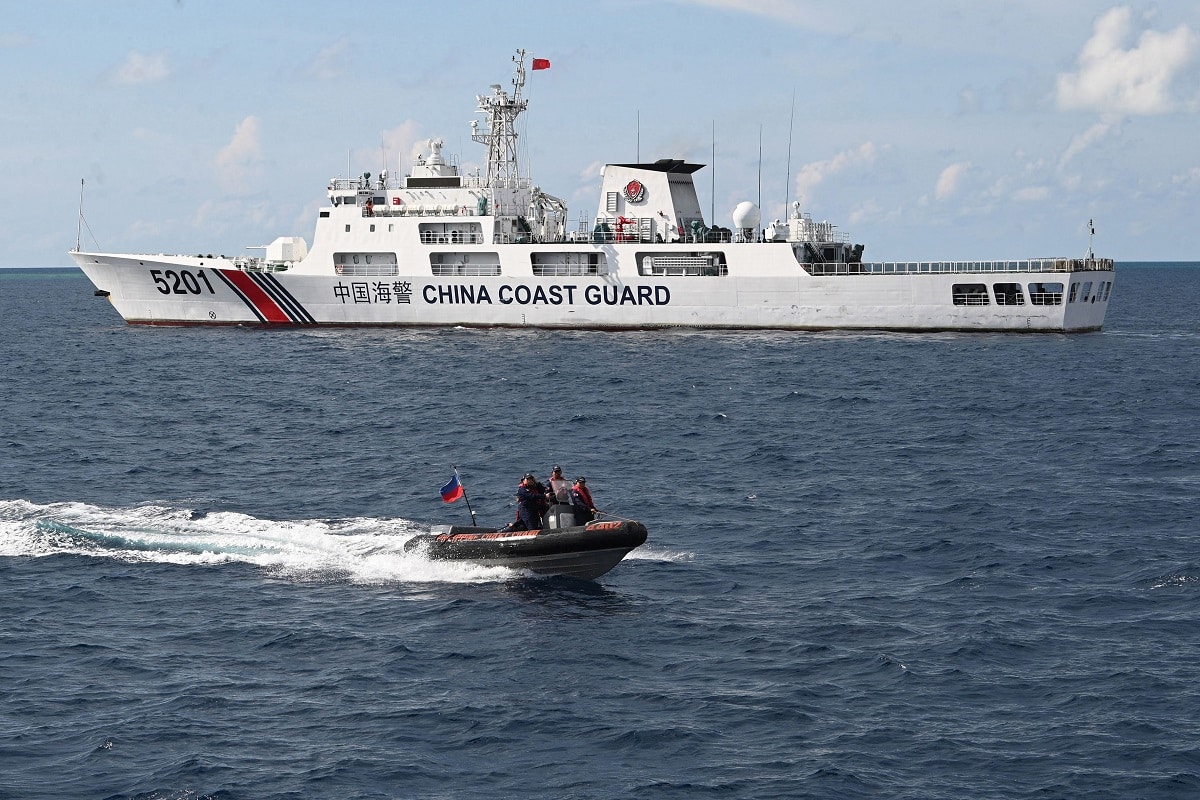 This photo taken on April 23, 2023 shows Philippine coast guard personnel aboard their rigid inflatable boat speeding past a Chinese coast guard ship after conducting a survey at Second Thomas Shoal in the Spratly Islands in the disputed South China Sea. - AFP was one of several media outlets invited to join two Philippine Coast Guard boats on a 1,670-kilometre (1,040-mile) patrol of the South China Sea, visiting a dozen islands and reefs. Beijing claims sovereignty over almost the entire South China Sea, including the Spratly Islands, ignoring an international ruling that the assertion has no legal basis. (Photo by Ted ALJIBE / AFP) / To go with AFP SPECIAL REPORT by Cecil MORELLA (Photo by TED ALJIBE/AFP via Getty Images)