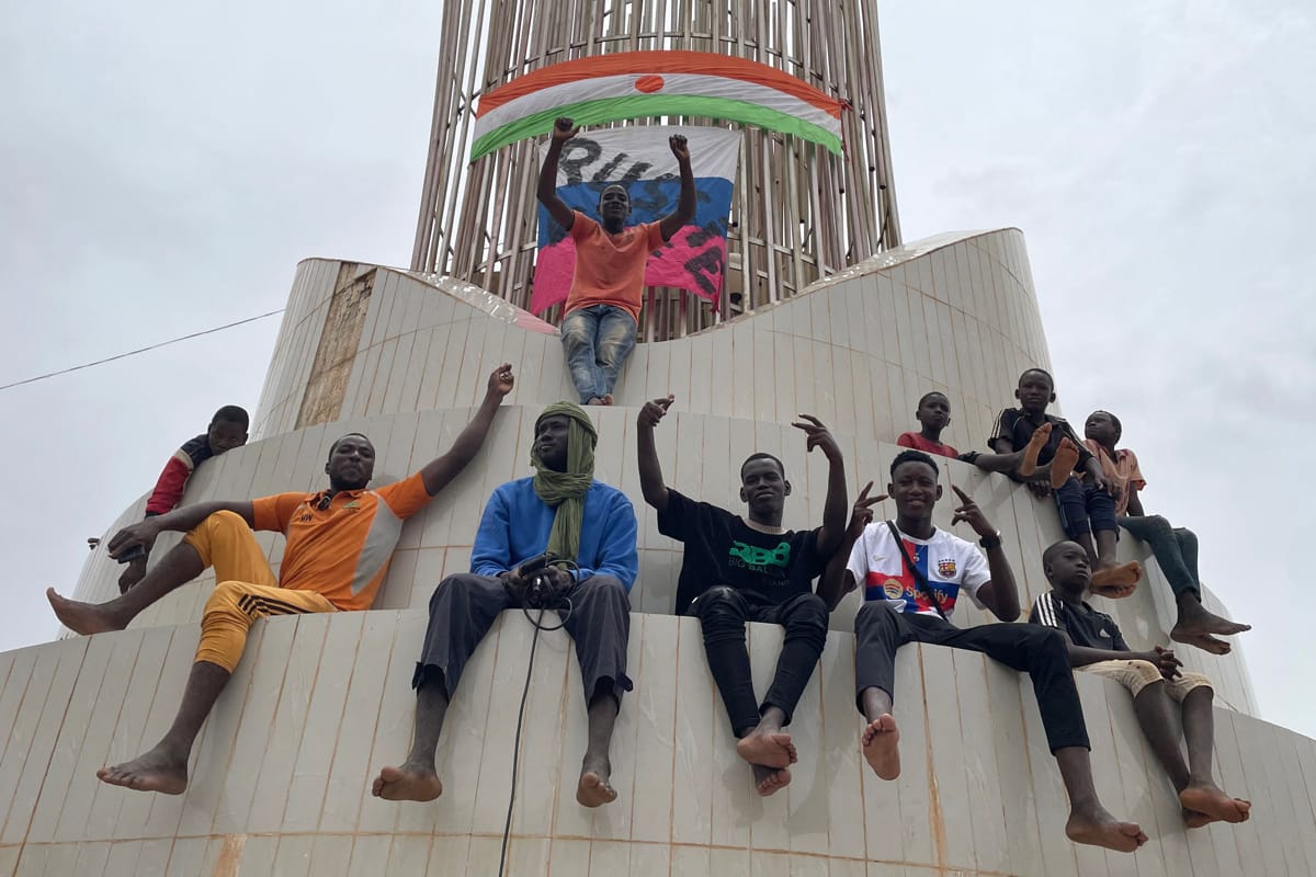 Supporters of the coup in Niger gather outside the national assembly in Niamey on 27 July, a make-shift Russian flag visible in the background (AFP via Getty Images)