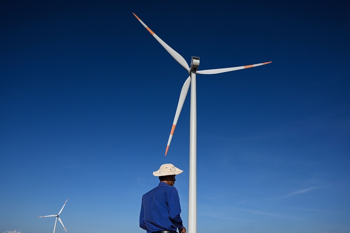  April 23, 2019 shows a man walking past wind turbines at the Phu Lac wind farm in southern Vietnam's Binh Thuan province. 