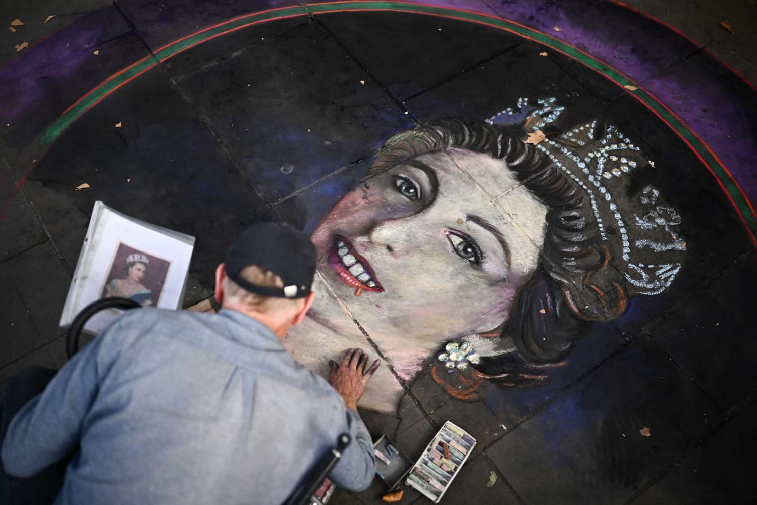 An artist draws a portrait of Britain’s Queen Elizabeth II on tiles with chalk at Trafalgar Square in London (Marco Bertorello/AFP via Getty Images)