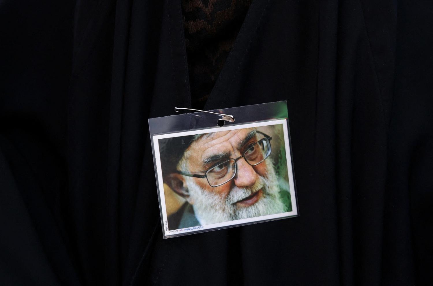 An Iranian pro-government protester wears a pin displaying a portrait of Supreme Leader Ayatollah Ali Khamenei during a rally against anti-government protests in Iran, 25 September 2022 (STR/AFP via Getty Images)