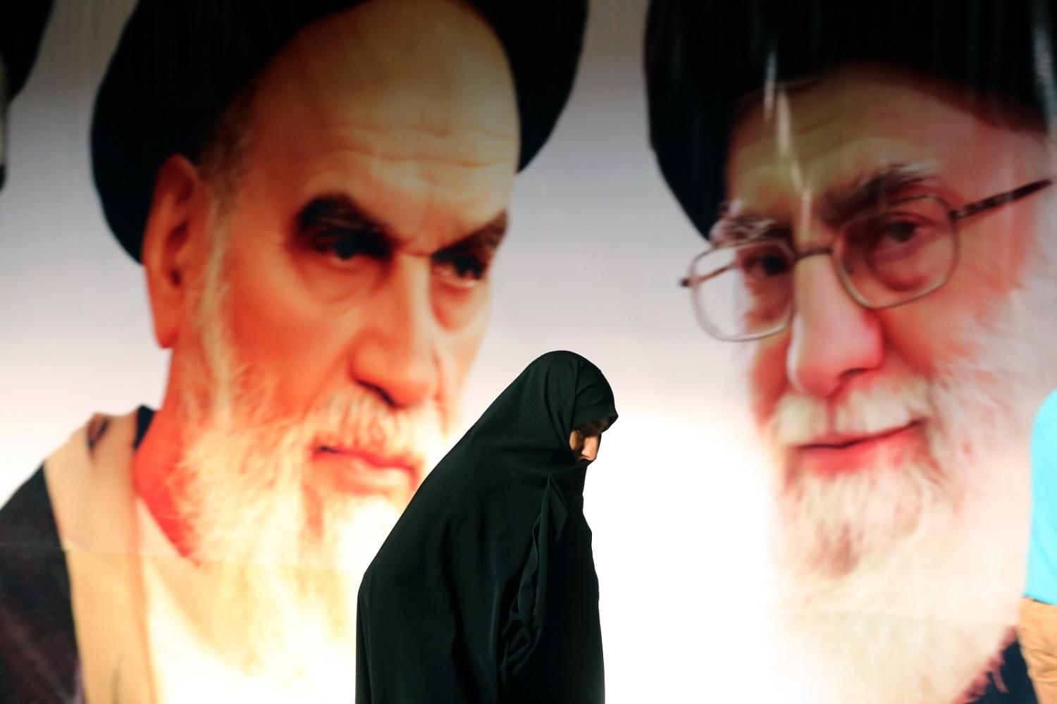An Iranian woman walks past a poster showing supreme leader Ayatollah Ali Khamenei (R) and the founder of Iran's Islamic Republic, Ayatollah Ruhollah Khomeini (L) (Atta Kenare/AFP via Getty Images)