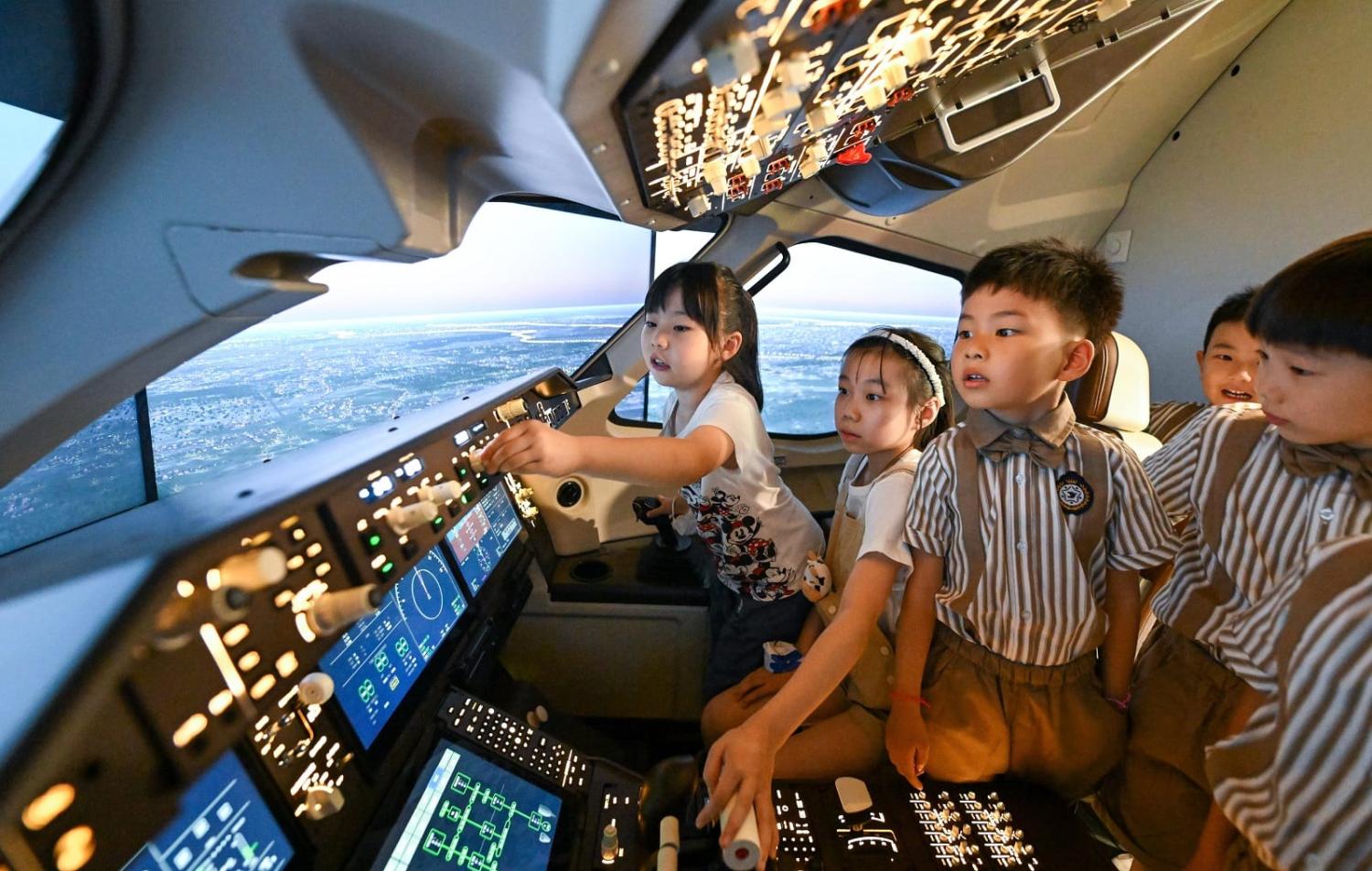 Children experience a flight simulator of the C919 at a science and technology museum in north China's Tianjin, 1 June 2023 (Sun Fanyue/Xinhua via Getty Images)