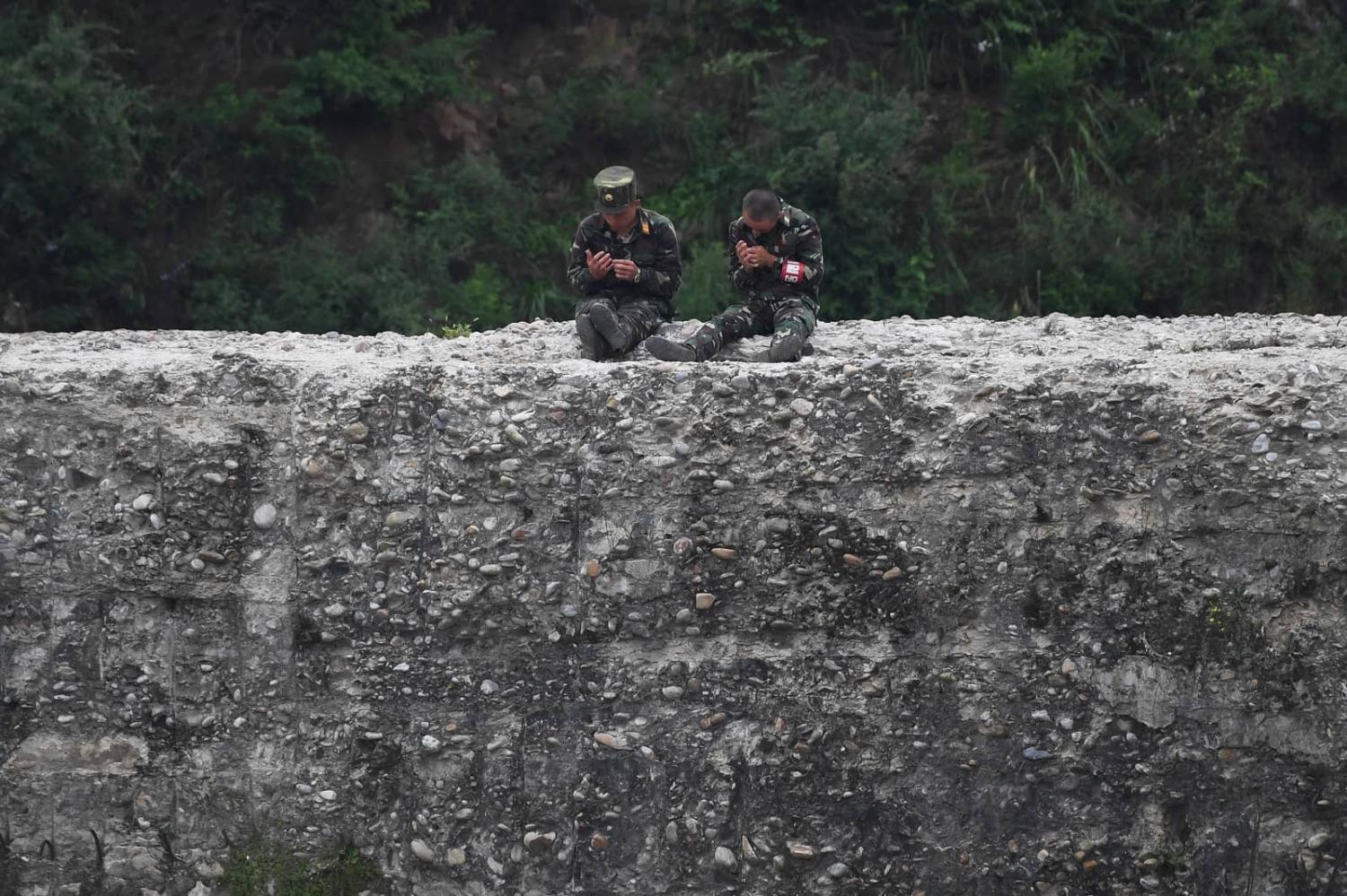 Controlling the border has been high on Kim Jong-un’s list of priorities during his tenure. North Korean soldiers sit on a wall of the Yalu river on the Chinese border, 5 September 2017 (Greg Baker/AFP via Getty Images)