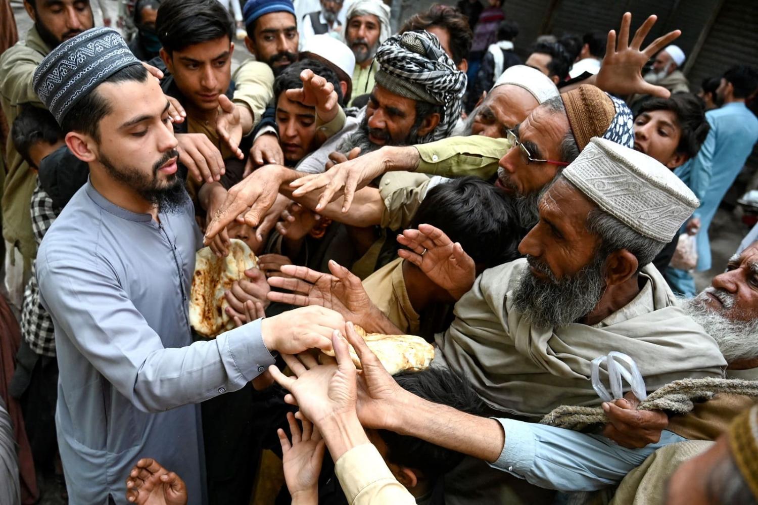 Men collect free bread from a distribution point in Peshawar on 3 April 2023. Pakistanis are feeling the brunt of the current economic turmoil (Abdul Majeed/AFP via Getty Images)