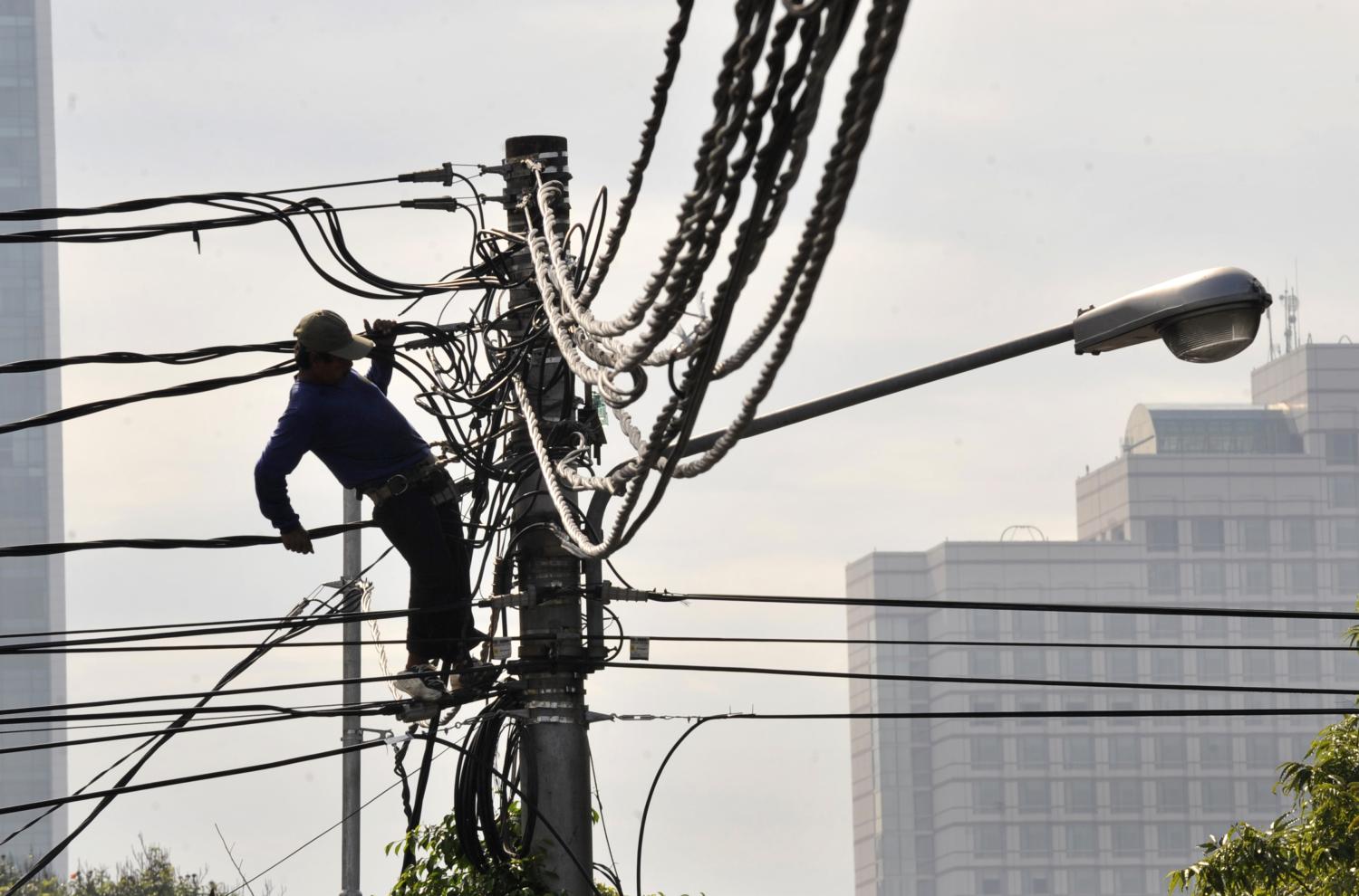 A lineman from the state-electricity company PLN installs new power cables in Jakarta (Romeo Gacad/AFP via Getty Images)