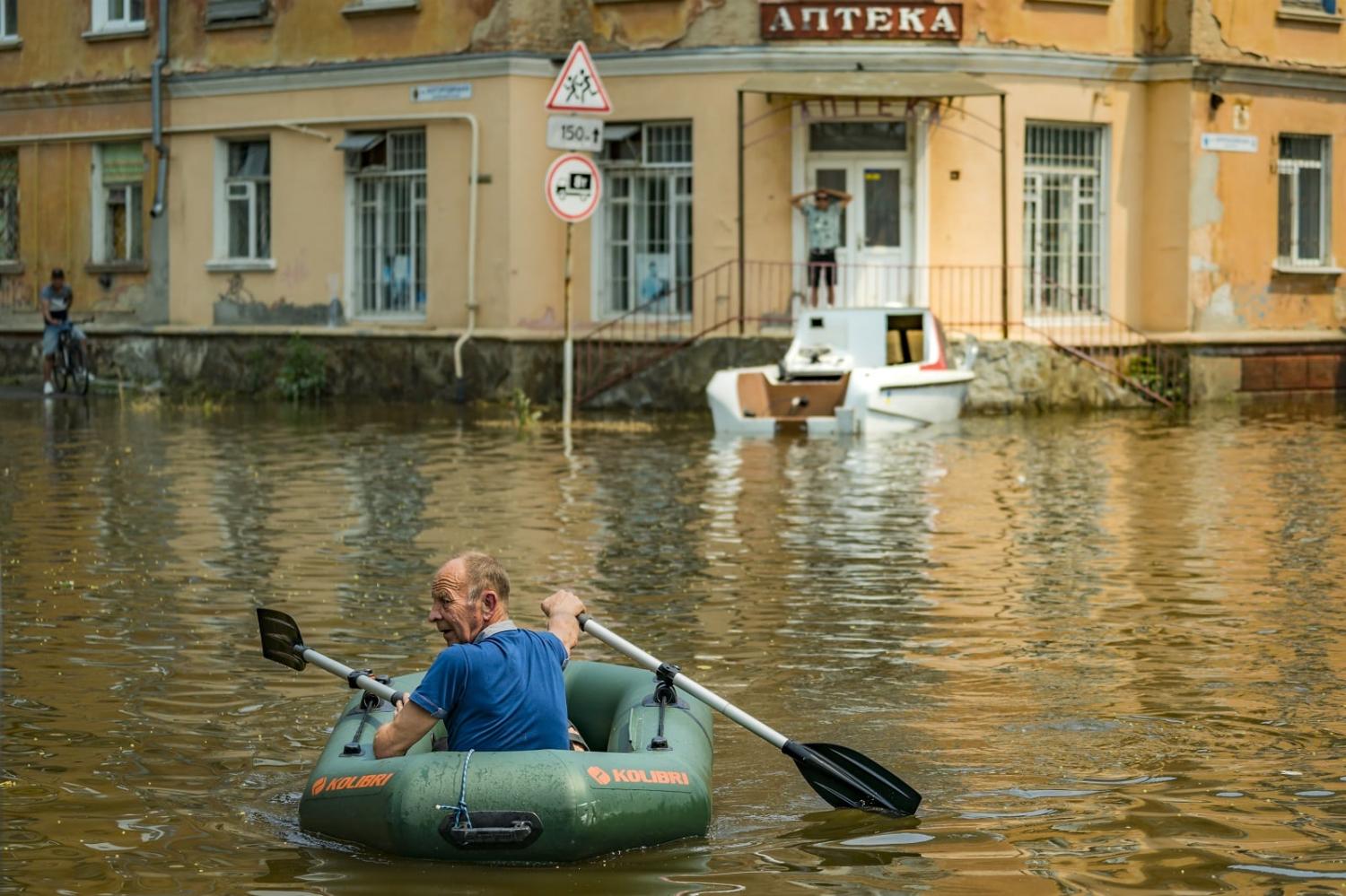 A man rows along a flooded street in Kherson city after the collapse of the Nova Kakhovka dam upstream, 9 June 2023 (Celestino Arce/NurPhoto via Getty Images)