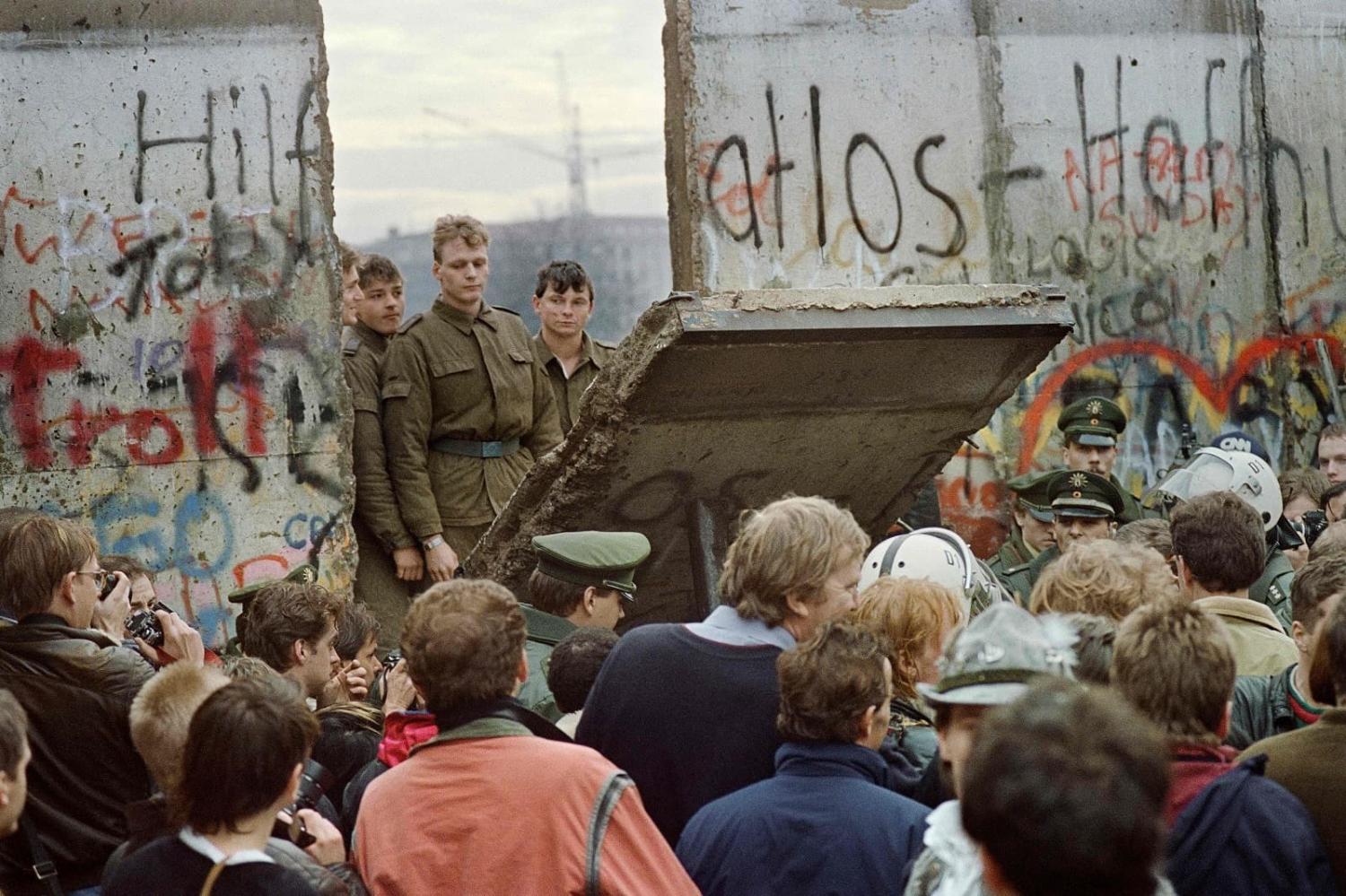 West Berliners gather at the Berlin Wall on 11 November 1989 to watch East German border guards open a crossing point between East and West near Potsdamer Square (Gerard Malie/AFP via Getty Images)
