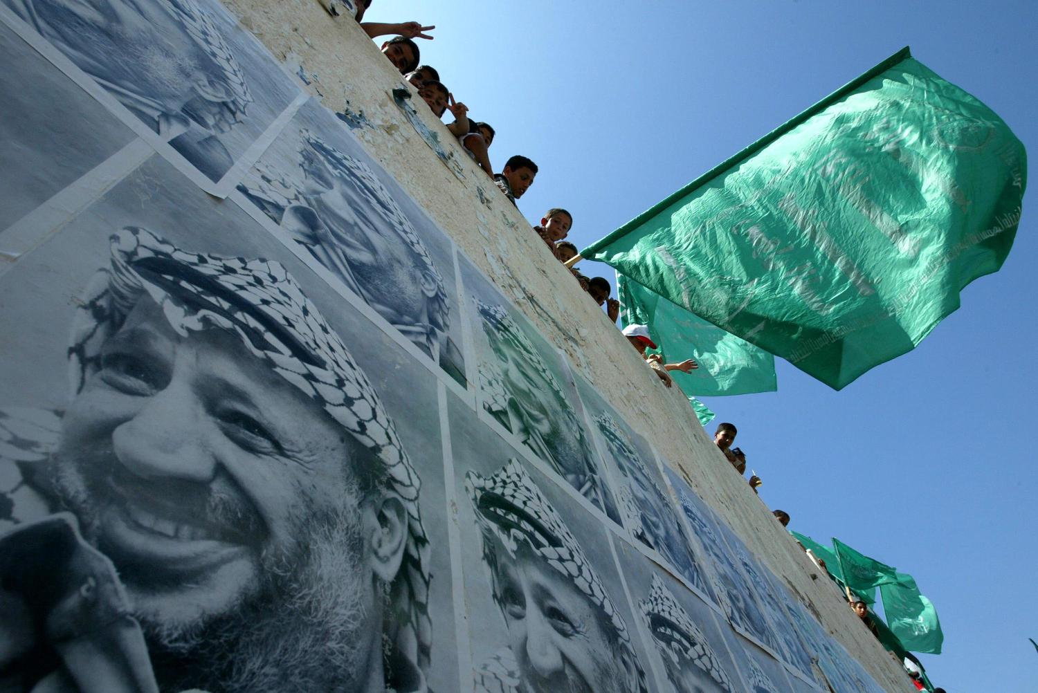 Palestinian supporters of Hamas wave an Islamic flag next to posters of Palestinian leader Yasser Arafat during a rally calling for the release of prisoners held in Israeli jails in 2003 in Gaza City. ( Abid Katib/Getty Images)