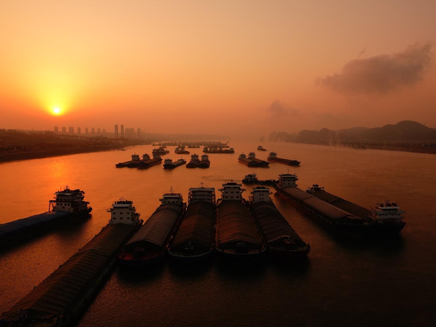 Cargo ships wait to pass through the Gezhouba lock on the Yangtze River at sunrise in Yichang, Hubei Province, China, on 19 December 2023 (Costfoto/NurPhoto via Getty Images)