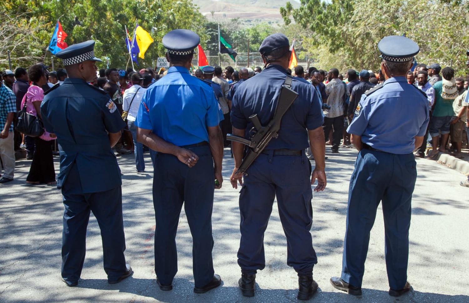 Papua New Guinea police officers watch on as hundreds of students marched towards the university gate in Port Moresby in 2013 to protest against Australia and PNG's asylum seeker plan (Ness Kerton/AFP via Getty Images)