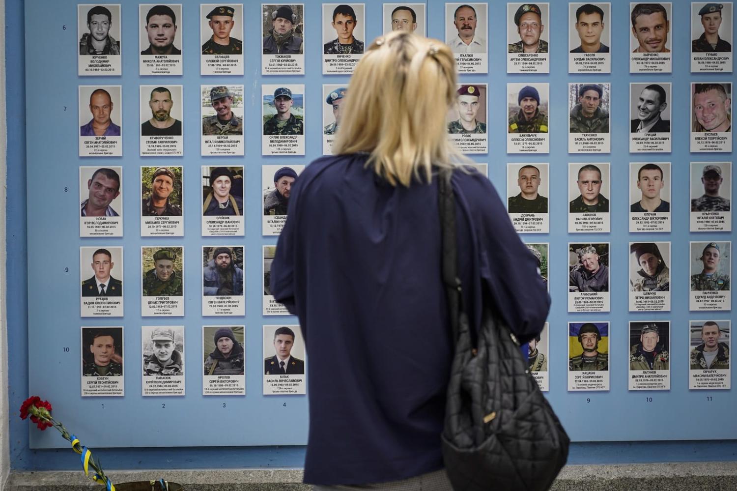 A woman looks at photos on the Wall of Remembrance of the Fallen for Ukraine on Mykhailivska Square in Kyiv (Oleg Pereverzev/Global Images Ukraine via Getty Images)