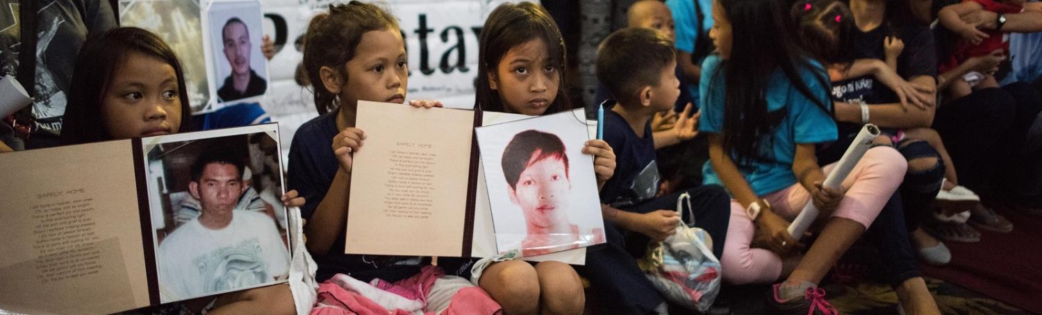Children hold pictures of loved ones killed during a mass held for victims of the drug war on 2 February in Manila. (Photo by Dondi Tawatao/Getty Images)