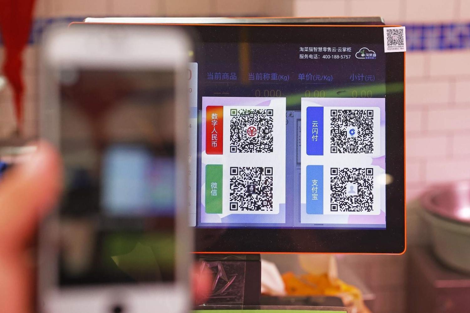 A customer chooses from QR payment codes for digital payment services e-CNY, UnionPay, Alipay and Wechat at a vegetable market in Shanghai on 7 May 2021 (Yin Liqin/China News Service via Getty Images)