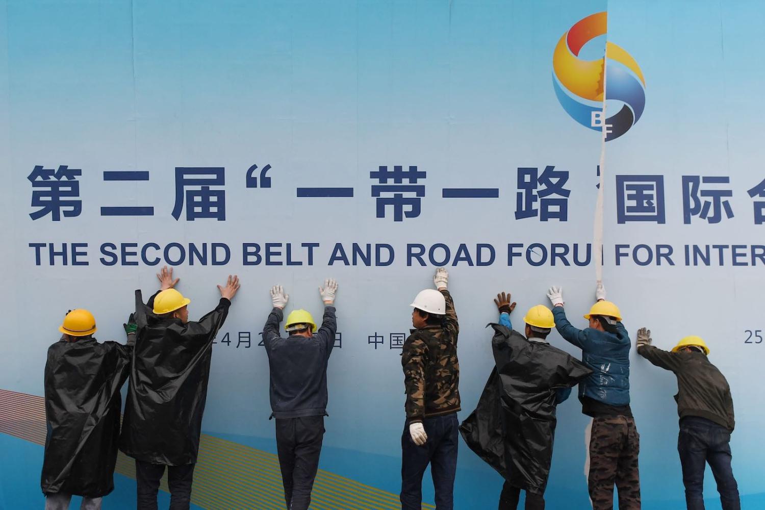 Workers take down a Belt and Road Forum panel outside the venue of the forum in Beijing in April (Photo: Greg Baker via Getty)
