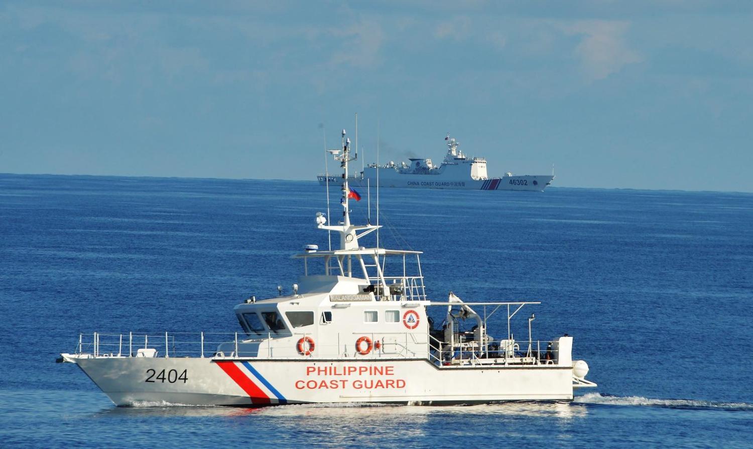 A Philippines coast guard ship sails past a Chinese coastguard ship near Scarborough shoal in the South China Sea in May 2019 (Ted Aljibe/AFP via Getty Images)