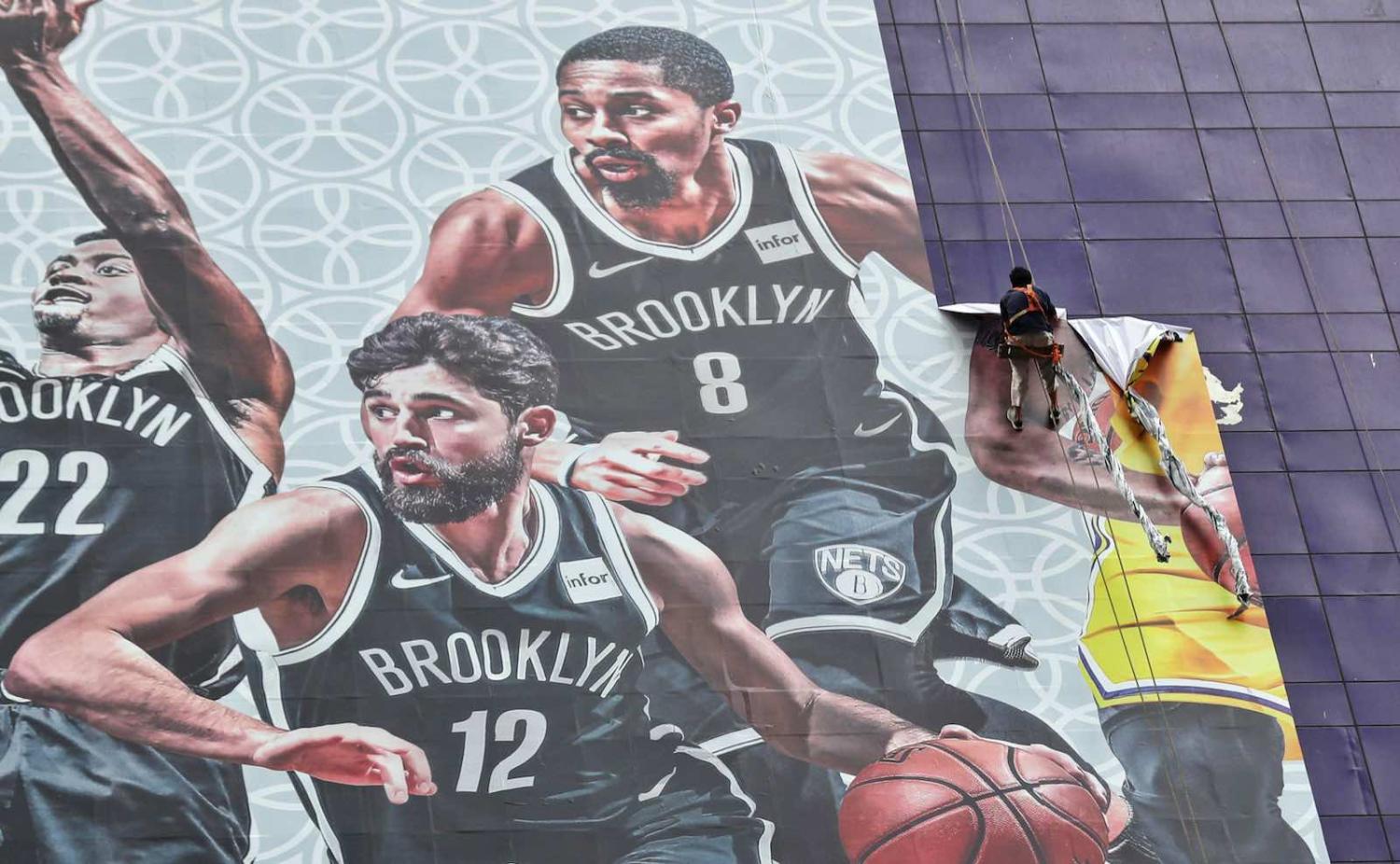 A worker removes a poster promoting an exhibition game between the Brooklyn Nets and the Los Angeles Lakers, Shanghai, 9 October 2019 (Photo: Zhang Hengwei via Getty Images)