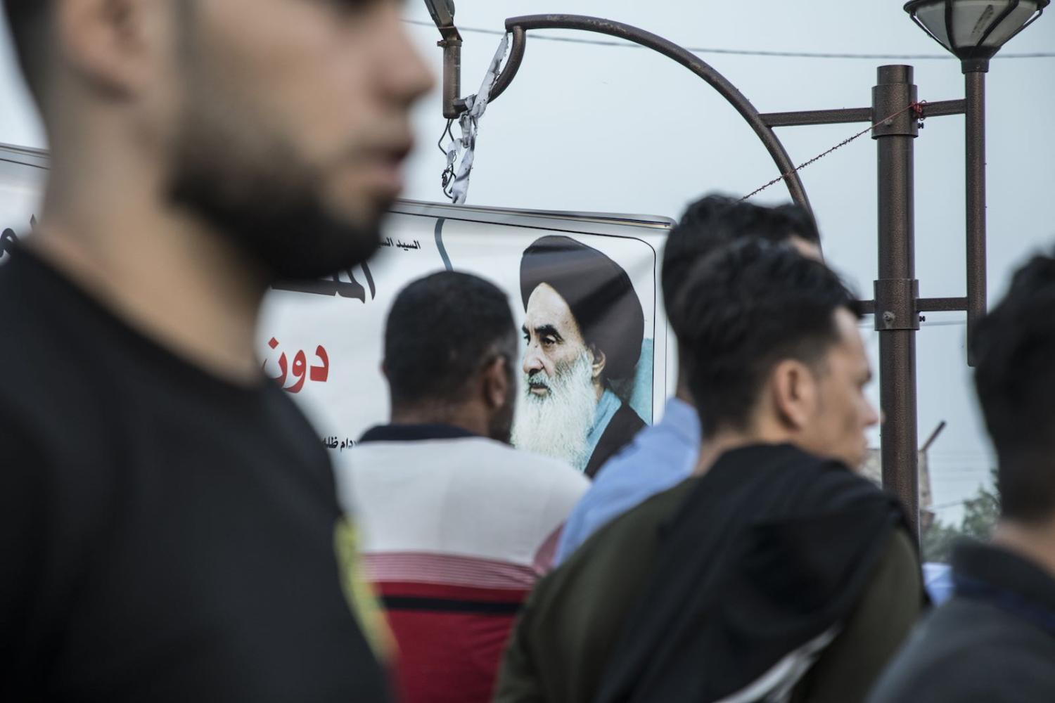 Protestors in front of the governorate in Basra, Iraq, and a billboard of Shia leader Ali Al-Sistani, 16 November (Photo: Laurent Van der Stockt/Le Monde/Getty Images)
