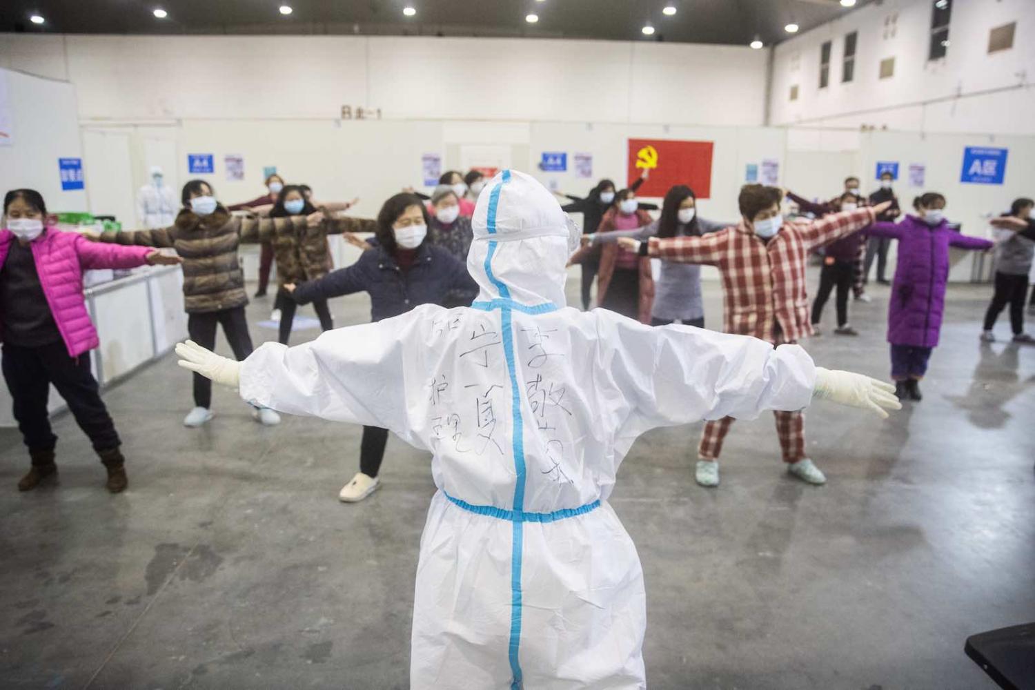 Medical staff lead patients with mild symptoms of the COVID-19 coronavirus in group exercises at an exhibition centre converted into a hospital in Wuhan, Hubei province (STR via Getty Images)