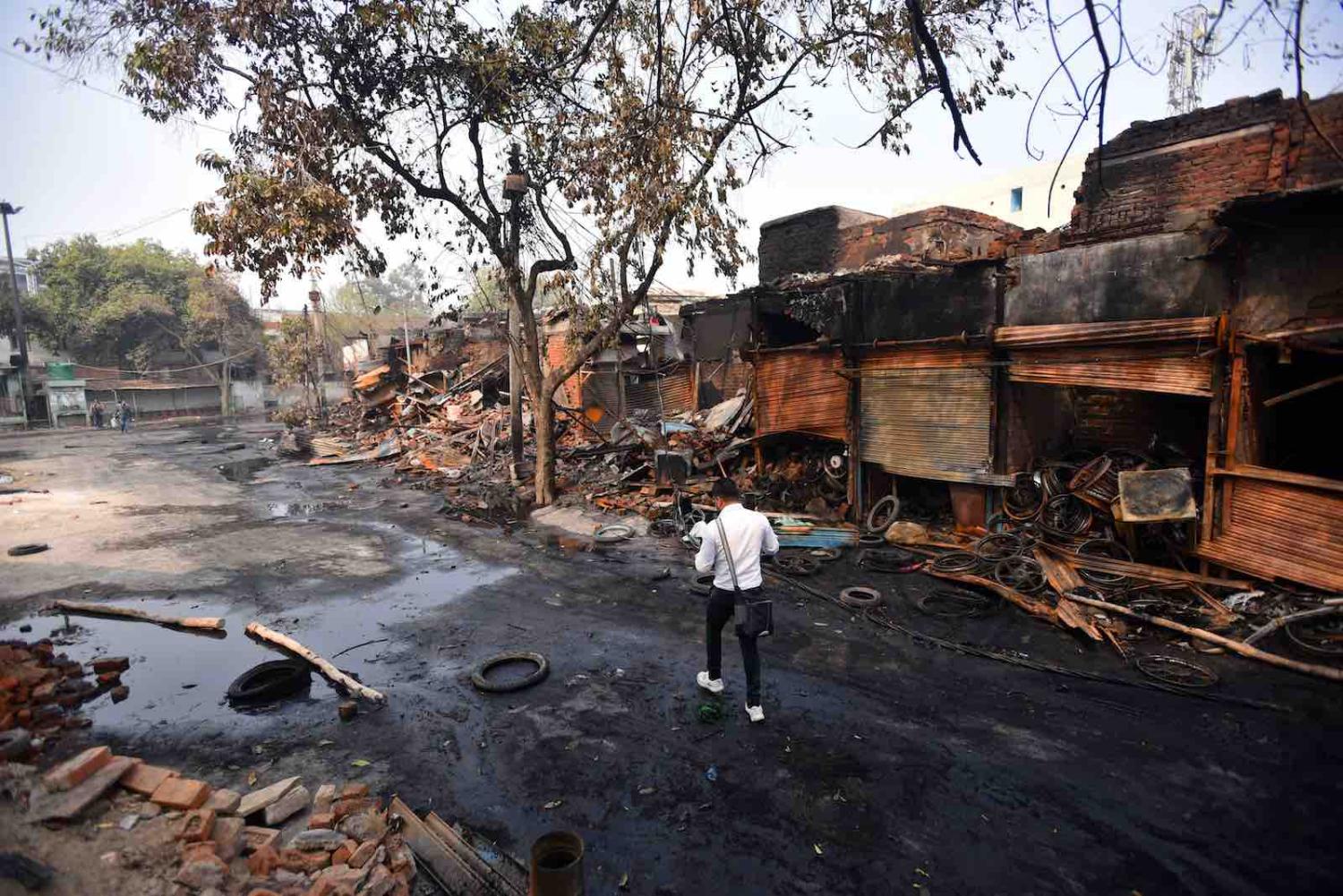 A man walks past shops burnt during sectarian riots in New Delhi, 26 February (Amal KS/Hindustan Times via Getty Images)