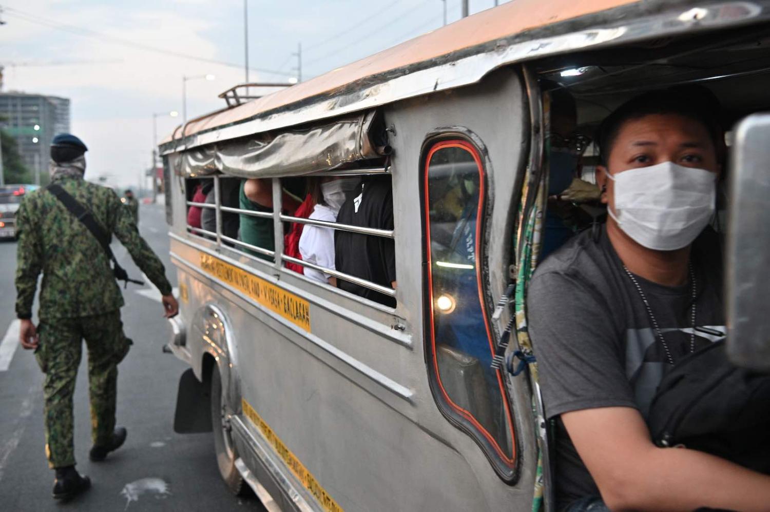 A policeman inspects a jeepney at a checkpoint in Manila, 15 March 2020 (Ted Aljibe/AFP via Getty Images)