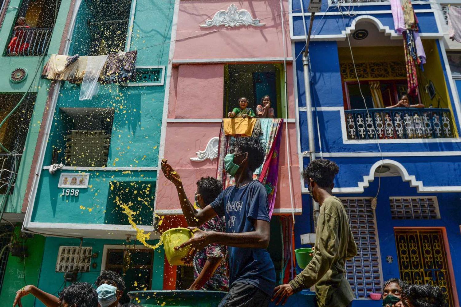 Children throw a mixture of water, neem herb, and turmeric in what is said to be a natural disinfectant on a Chennai street during a government-imposed nationwide lockdown (Arun Sankar/AFP/Getty Images)