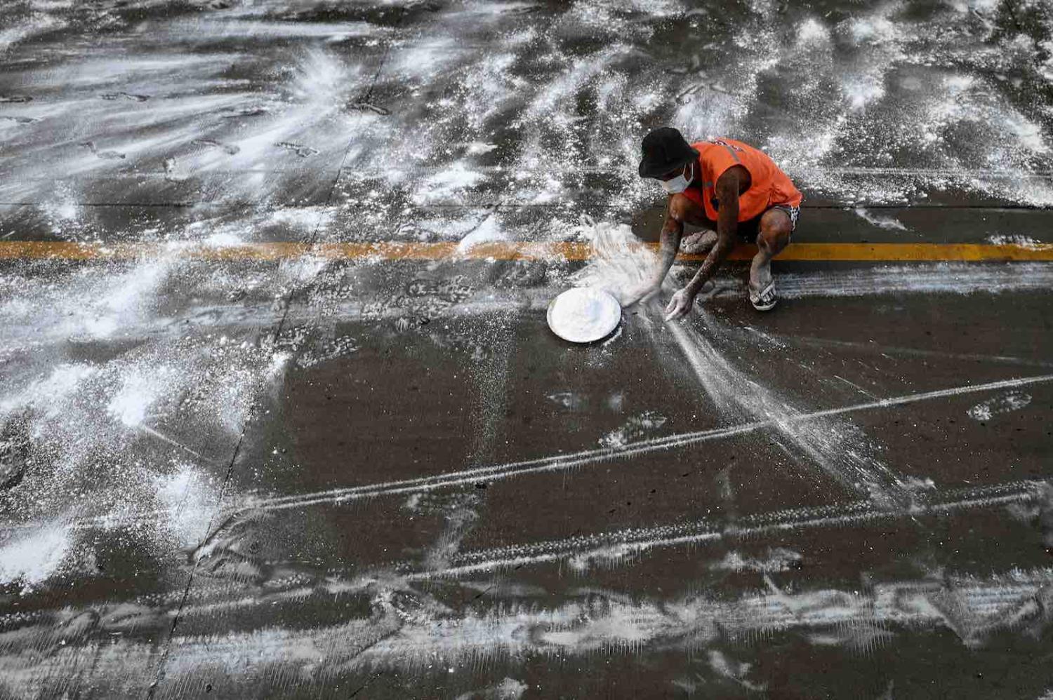 A volunteer spreads lime on a road as a preventive measure against Covid-19, Yangon, 22 April (Ye Aung Thu/AFP via Getty)