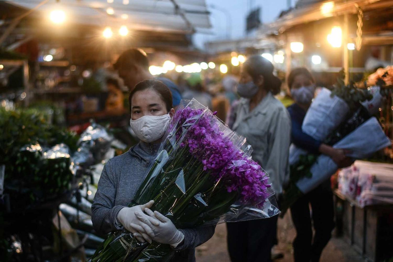 A woman carries flowers at the Quang Ba flower market in Hanoi, 11 May (Manan Vatsyayana/AFP via Getty Images)