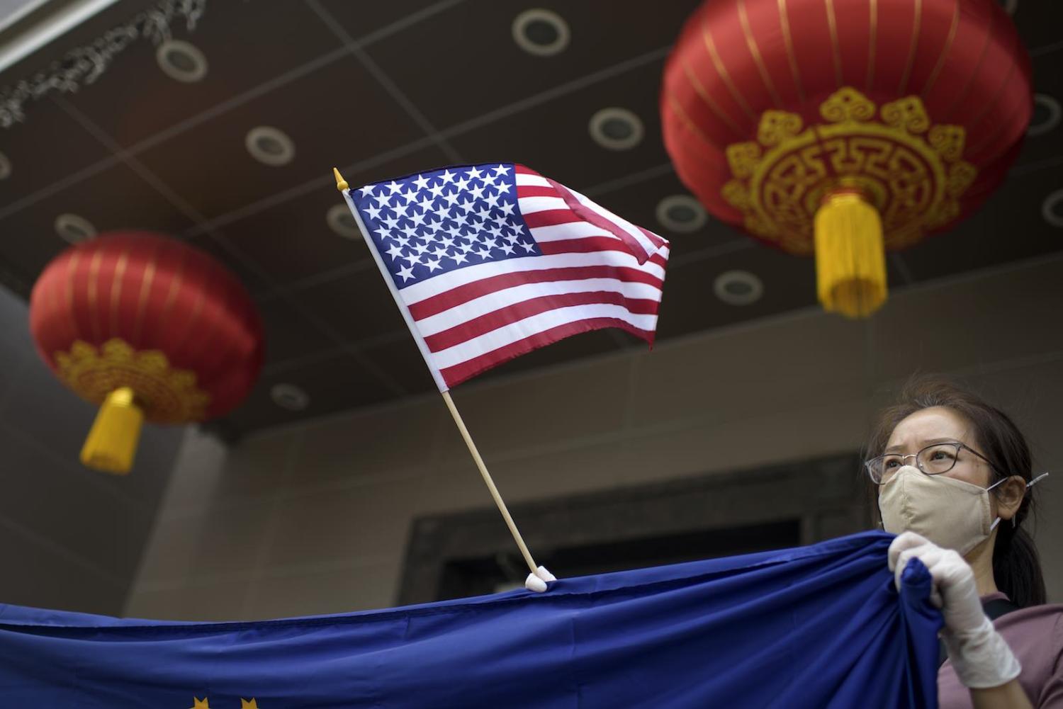 A protester holds a US flag outside of the Chinese consulate in Houston after the Trump administration ordered it be closed (Mark Felix/AFP via Getty Images)