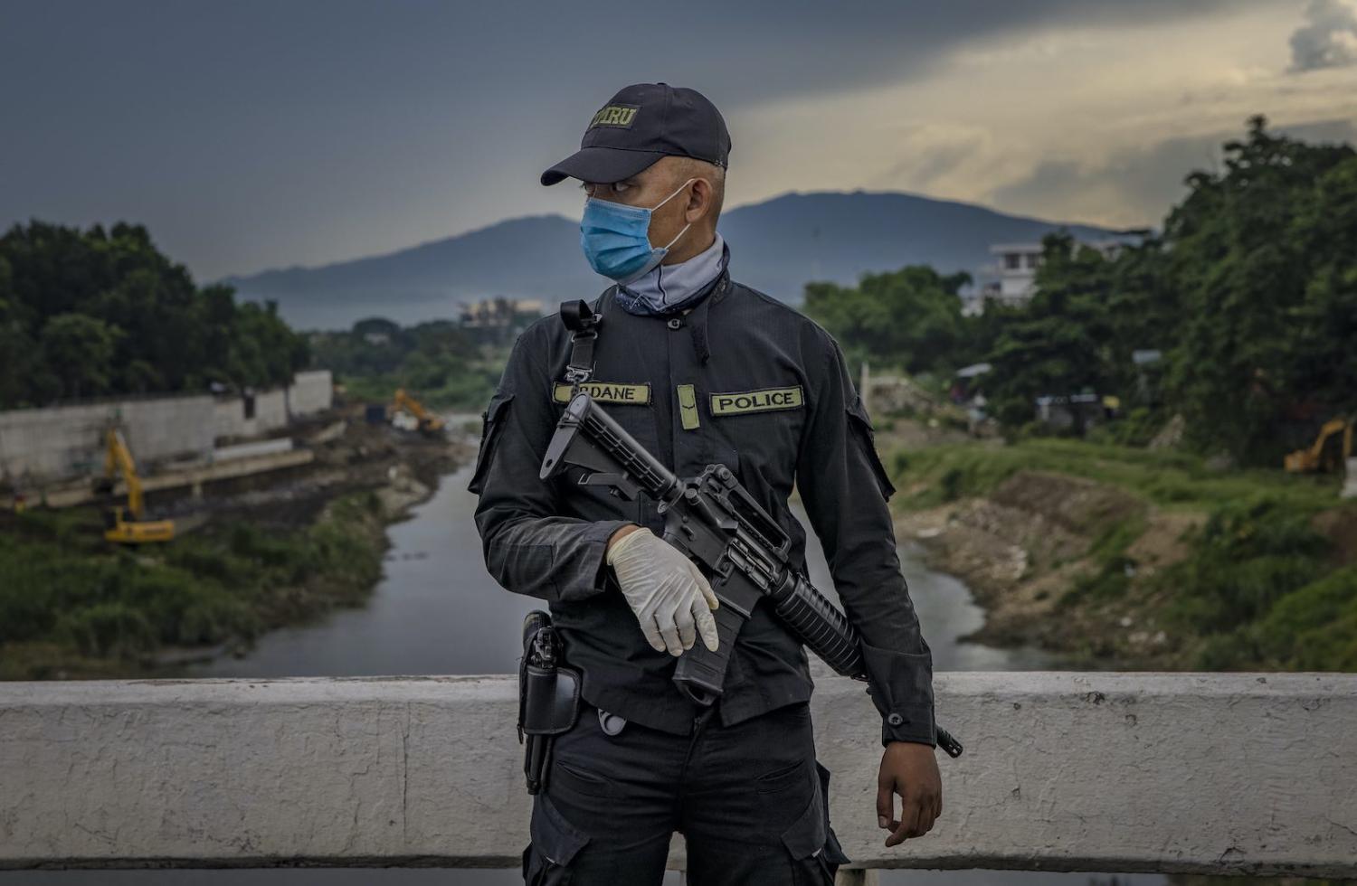 A police officer stands guard at a quarantine checkpoint in Quezon city, Philippines, 4 August 2020 (Ezra Acayan/Getty Images) 
