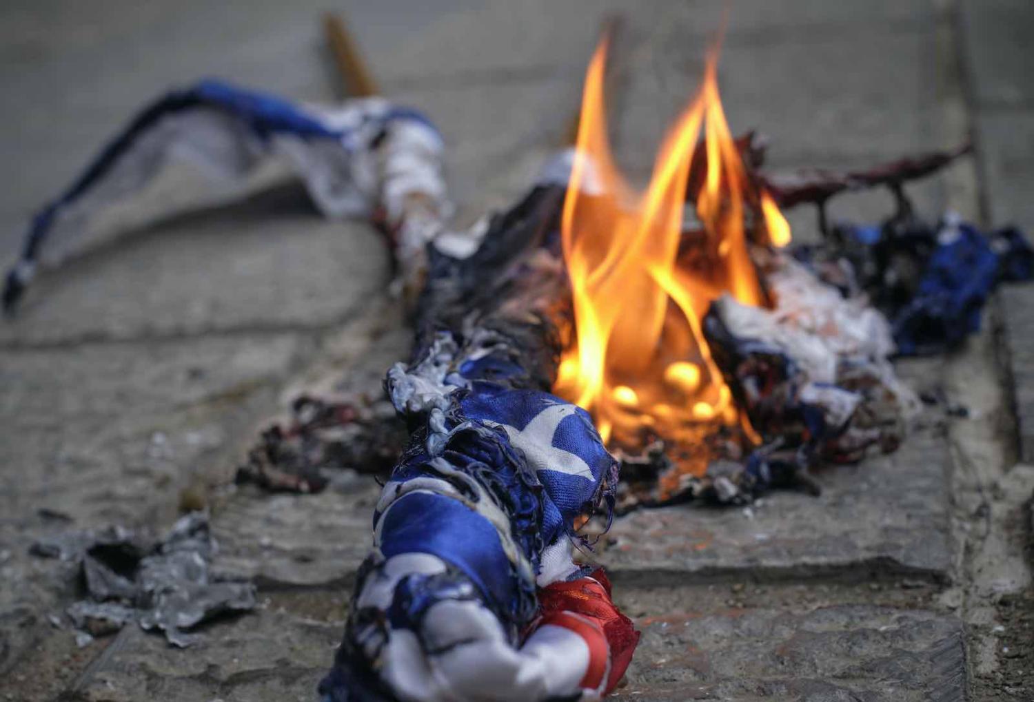 Demonstrators set fire to US and Israel flags outside the Iranian Foreign Ministry in Tehran on 28 November, following the assassination of Mohsen Fakhrizadeh (Morteza Nikoubazl/NurPhoto via Getty Images)