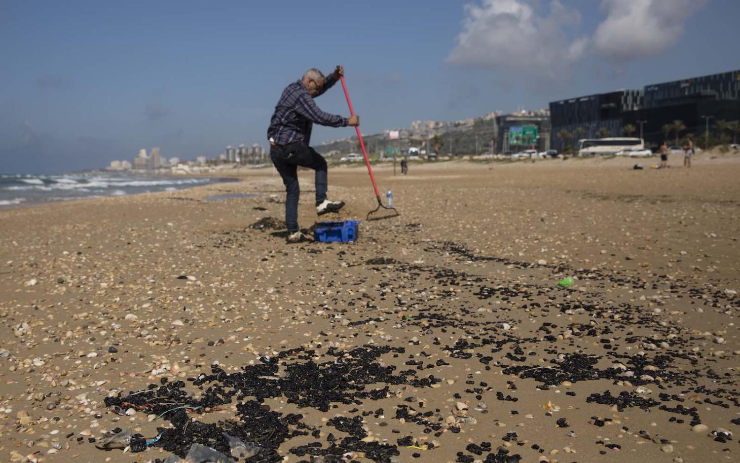 Cleaning tar from a beach in Haifa, Israel, following a suspicious oil spill in the Mediterranean, 25 February (Amir Levy/Getty Images)