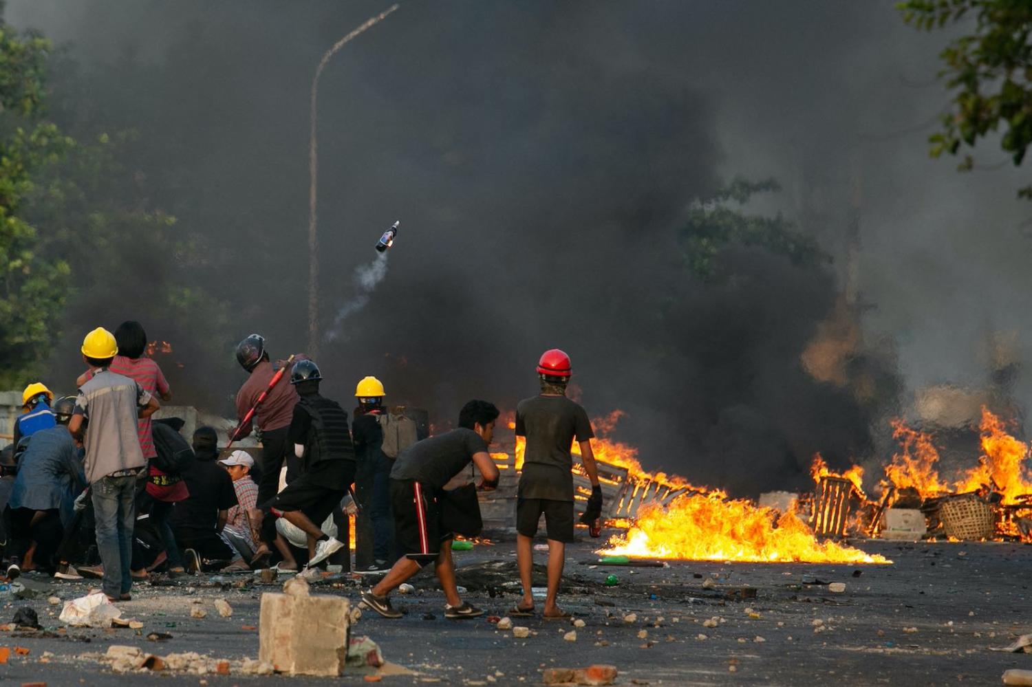 A protester throws a petrol bomb as others take cover behind homemade shields as they confront the police during a crackdown on demonstrations against the military coup in Yangon on 16 March (STR/AFP via Getty Images)