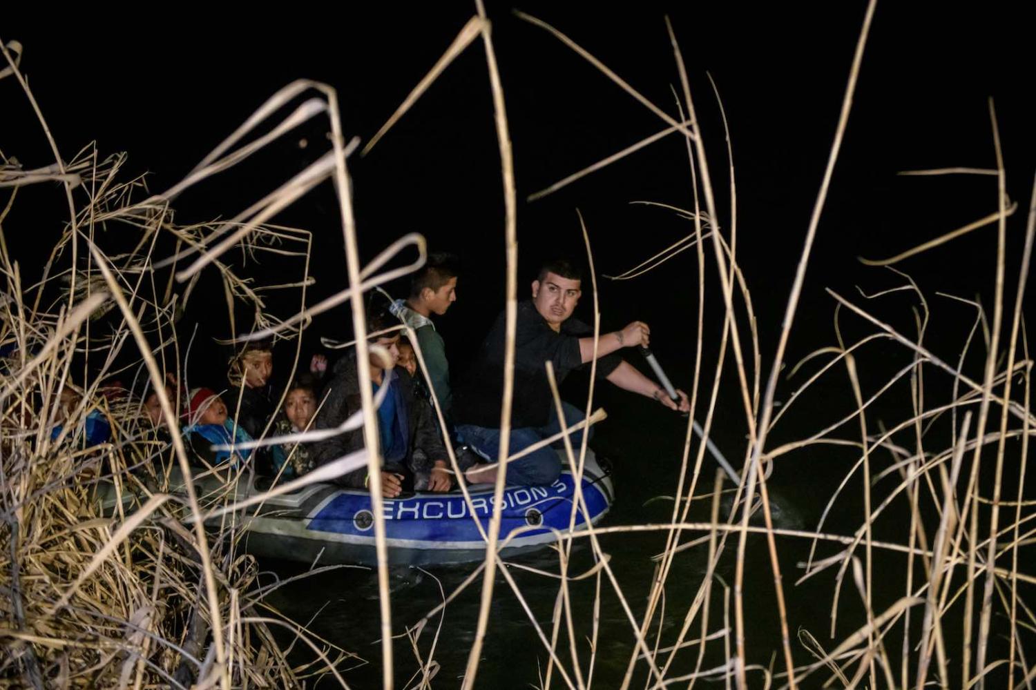 Honduran and Guatemalan asylum seekers arrive from Mexico in an inflatable boat as a “coyote” people smuggler steers towards the US side of the Rio Grande river in Roma, Texas, 28 March 2021 (Ed Jones/AFP via Getty Images)