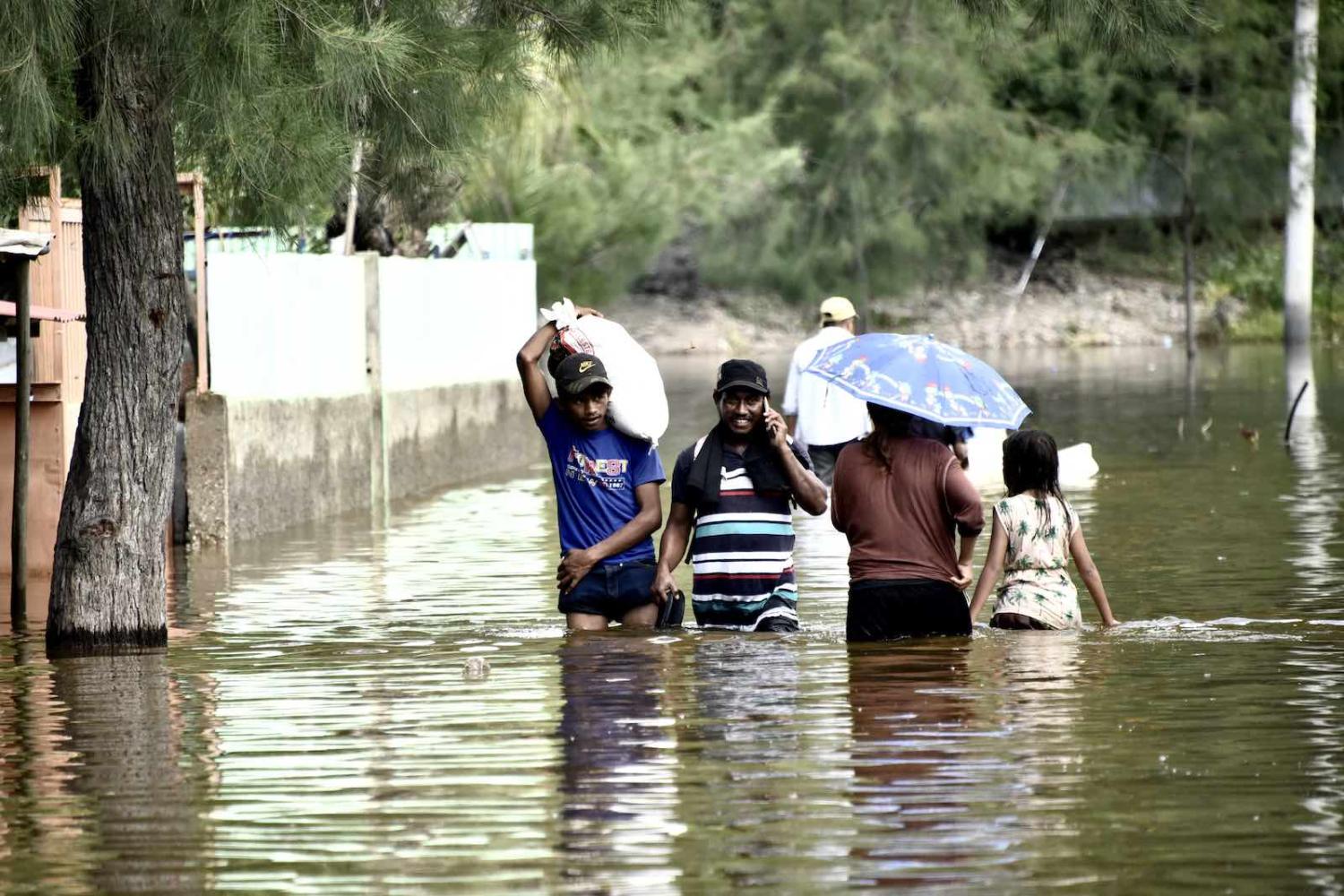 Dili residents wade through a flooded street on 9 April 2021 (Valentino Dariel Sousa/AFP via Getty Images)