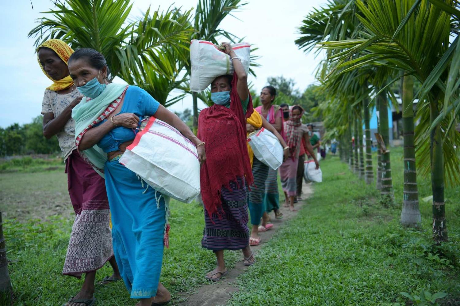 Residents carry food distributed by an NGO after the government eased Covid-19 restrictions in Jampuijala, India, 16 June 2021 (Str/Xinhua via Getty Images)