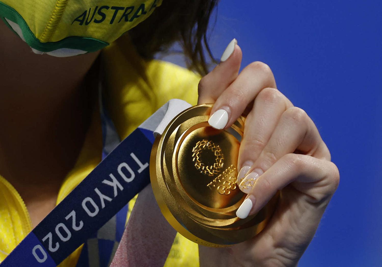Australia’s Kaylee McKeown holds up her gold medal after the final of the women’s 100 metre backstroke swimming event at the Tokyo 2020 Olympic Games (Odd Andersen/AFP via Getty Images)