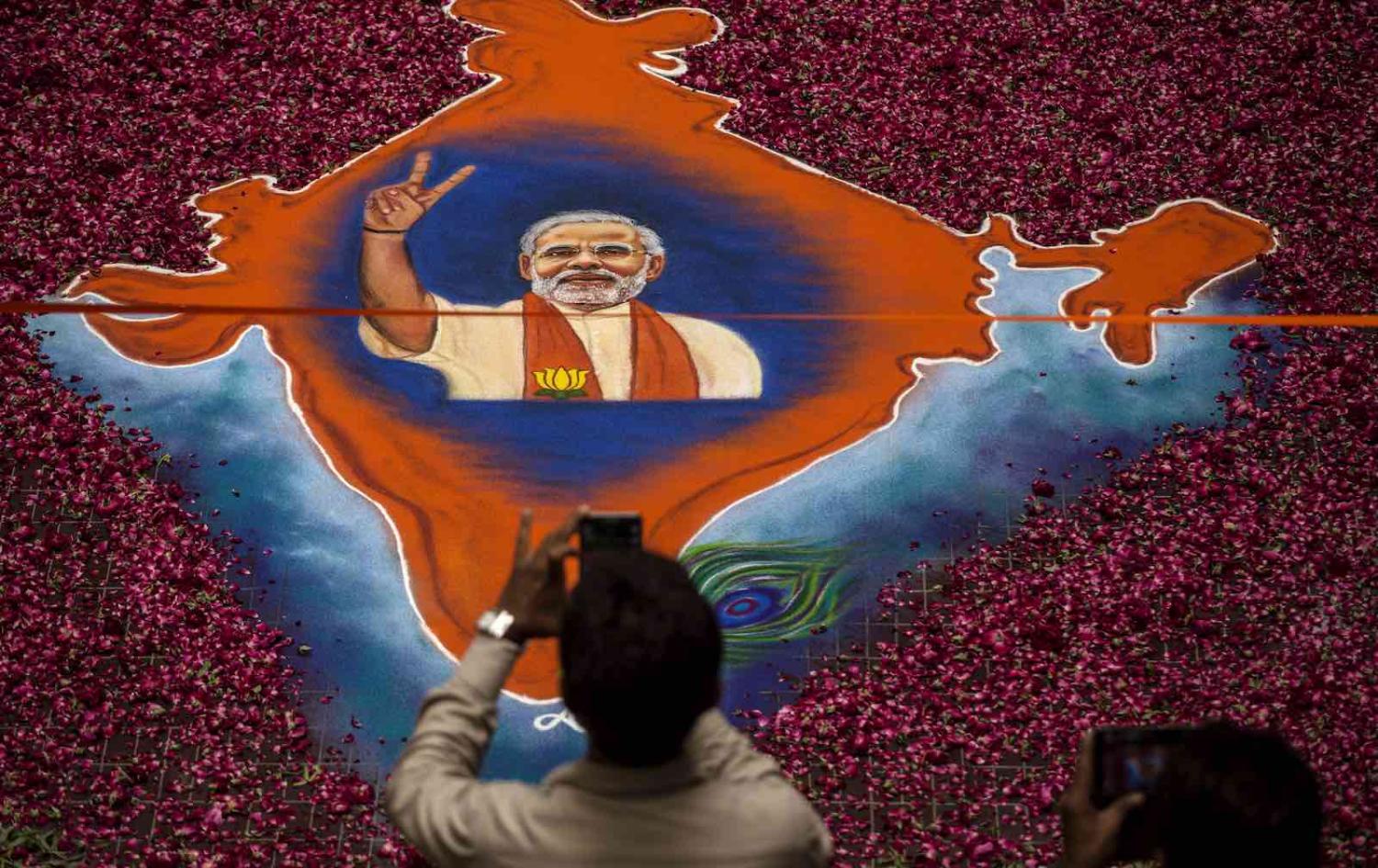 A supporter takes a picture of a map of India made of flowers with a picture of BJP leader Narendra Modi in Ahmedabad, India during the 2014 elections (Photo: Kevin Frayer/Getty)