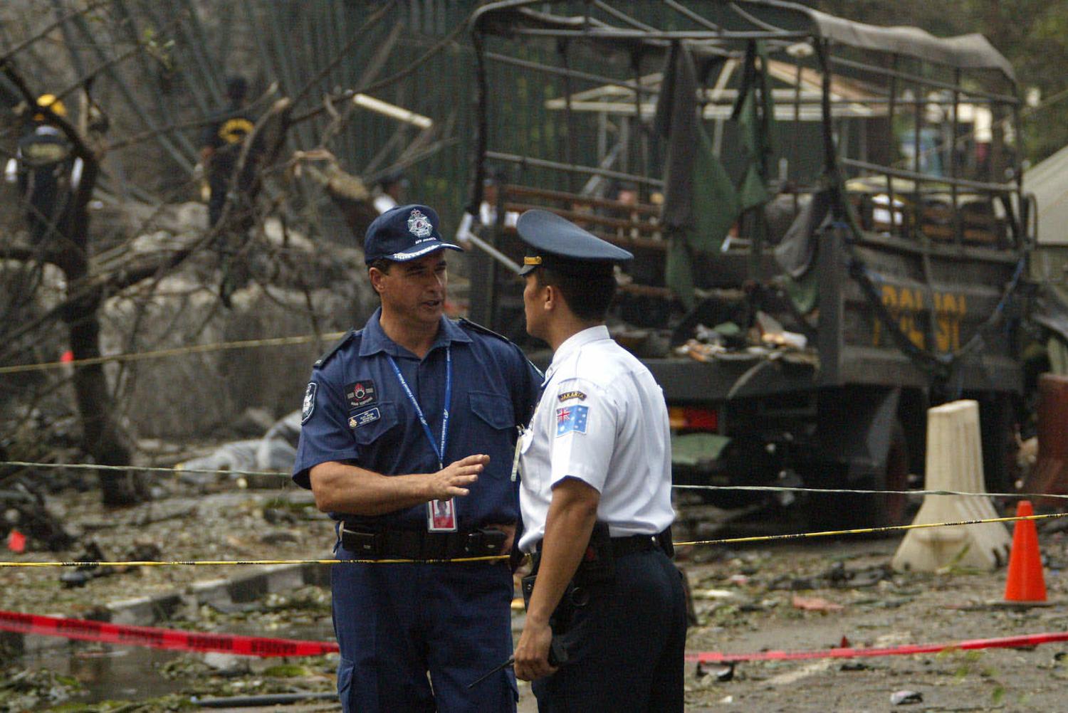An Australian Federal Police officer, left, speaks with a security guard the day after the bombing of the Australian Embassy in Jakarta, Indonesia, on 9 September 2004 (Dimas Ardian/Getty Images)
