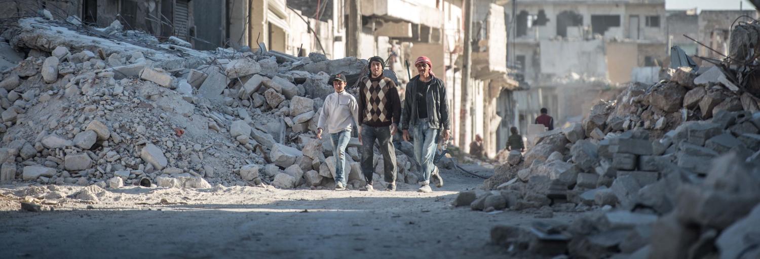 Syrians walk past damaged houses in Al-Bab district of Aleppo, Syria (Photo: Kerem Kocalar/Anadolu Agency/Getty Images)