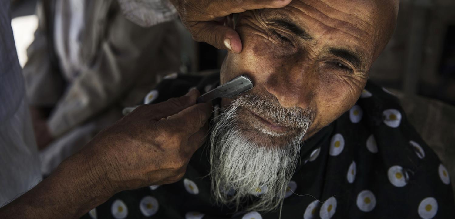 An ethnic Uighur man has his beard trimmed: religious observances such as having an “irregular beard” have become seen as “expressions of extremification” (Phtoto: Kevin Frayer via Getty)