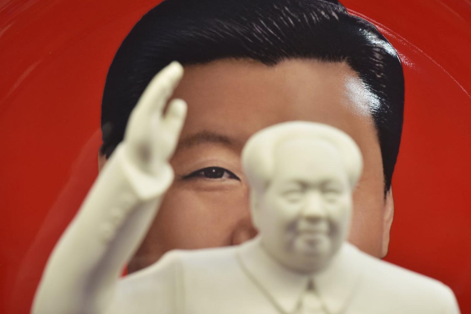 A decorative plate featuring an image of China’s President Xi Jinping is seen behind a statue of late communist leader Mao Zedong at a souvenir store next to Tiananmen Square in Beijing (Greg Baker/AFP/Getty Images)