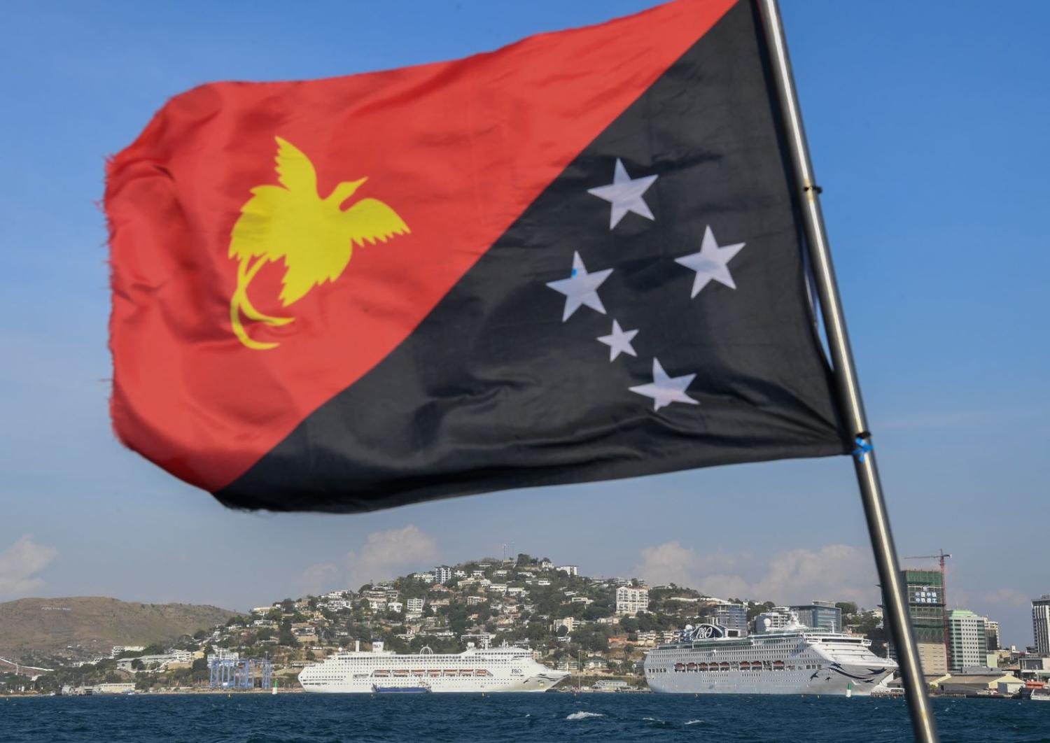 The national flag of PNG flies in front of cruise ships docked for the 2018 APEC Summit in Port Moresby. (Photo: James Morgan/Getty)