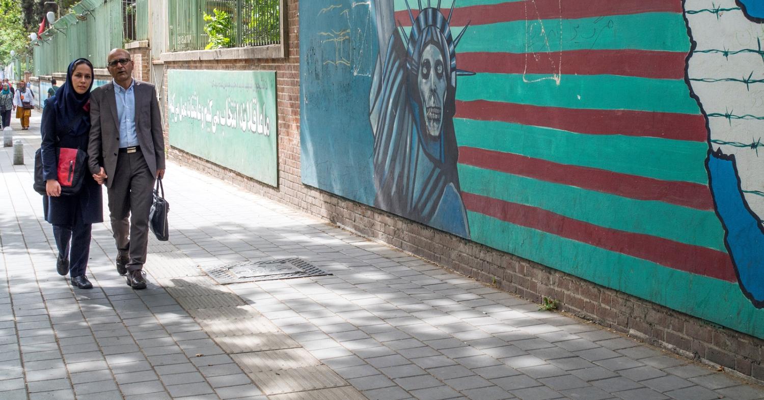 Pedestrians walk past a painting of the Statue of Liberty as a skeleton outside the former American embassy in Tehran. (Photo by Leisa Tyler/Getty Images)