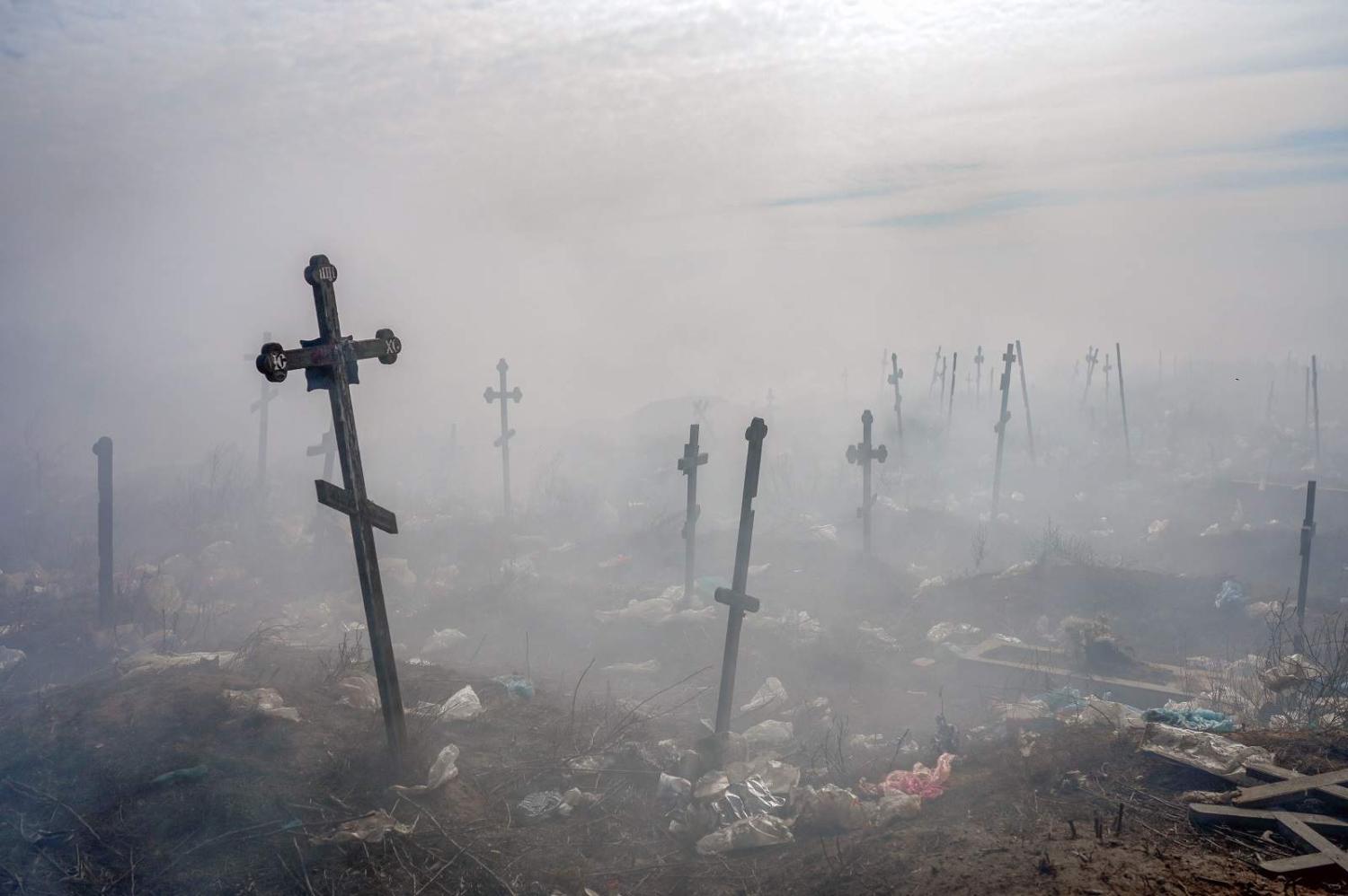 Smoke from burning debris fills a cemetery in Mykolaiv, southern Ukraine, 21 March 2022 (Bulent Kilic/AFP via Getty Images)