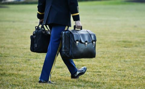 A military aide carries the nuclear “football” with the equipment and nuclear codes which is said to always accompany the US president (Mandel Ngan/AFP via Getty Images)